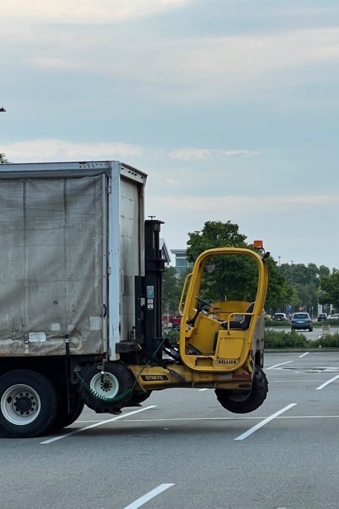 Side view of a truck with a forklift attached, parked in a spacious empty lot.